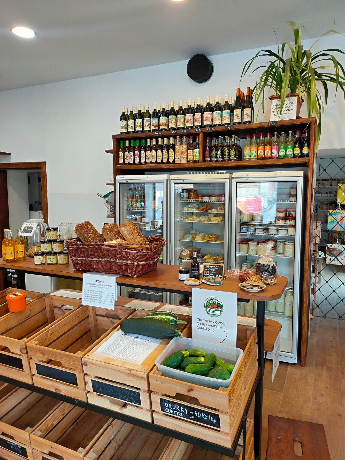 pohled na čerstvou zeleninu v bedýnkách a v pozadí lednice plné čerstvého zboží